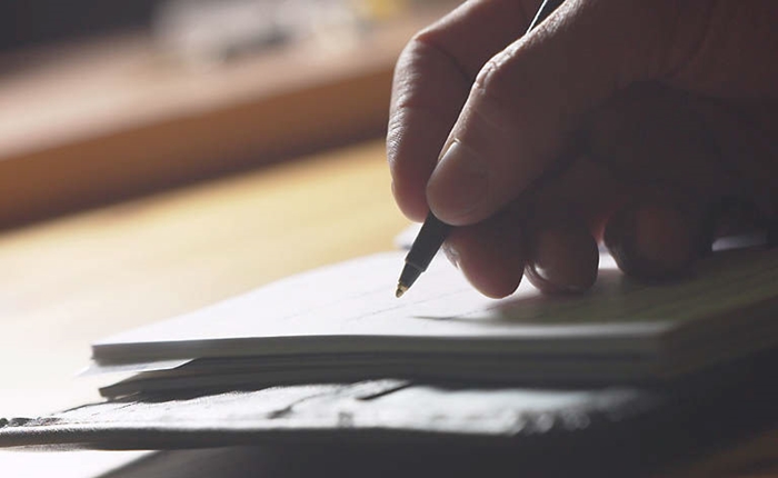 Person-writing-in-book-700