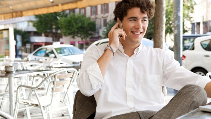 efficient-businessman-making-a-call-on-his-smart-phone-and-using-a-laptop-computer-while-sitting