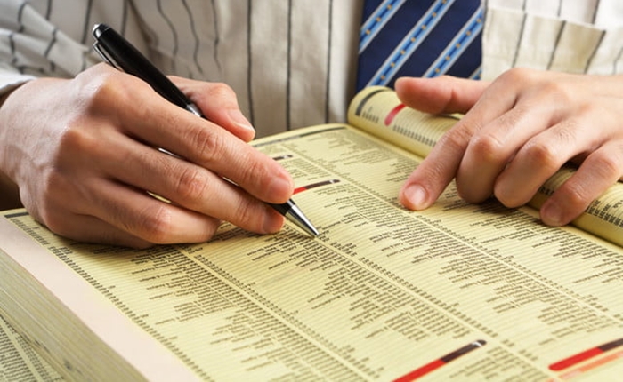 7284623-businessman-searching-for-something-in-yellow-pages-through-indexes-700