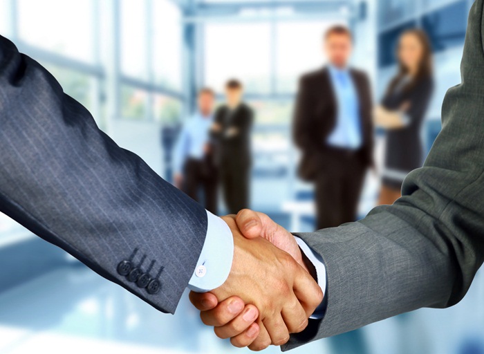 Business associates shaking hands in office