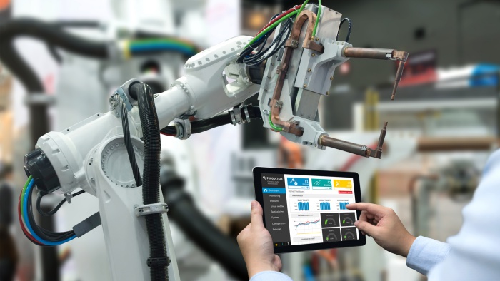 Engineer hand using tablet, heavy automation robot arm machine in smart factory industrial with tablet real time monitoring system application. Industry 4th iot concept.